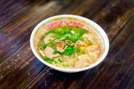 Fresh made thai vegetable dim sum noodle soup served with red pork slices, cilantro and bean sprouts. Traditional asian cuisine.の写真素材