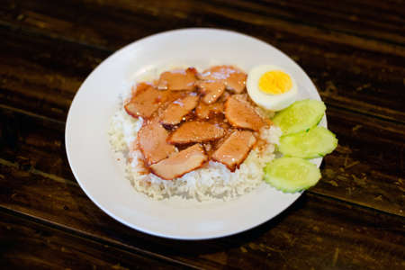 Fresh prepared asian sweet glazed pork fillet served with steamed jasmine rice, boiled egg and cucumber slices. Traditional thai cuisine made of fresh ingredientsの写真素材