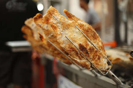 Preparing asian snapper fish covered by salt on barbeque. Traditional thai streetfood cuisine made of fresh ingredients.の写真素材