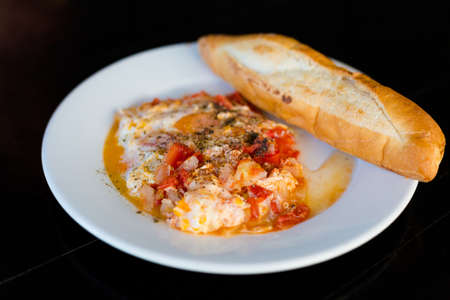 Fresh prepared asian spicy shakshuka tomato scramble egg served with crispy baguette. Traditional lao cuisine made of fresh ingredients.の写真素材