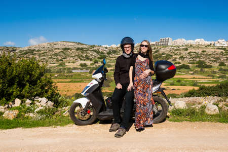 Beautiful landscape of Malta island and couple of young caucasian tourists traveling on motorbike....