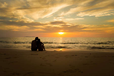 Summer landscape with young caucasian tourist couple watching golden sunset on tropical koh Kradan island in Thailand. Holiday photos taken in paradise scene during honeymoon.の写真素材
