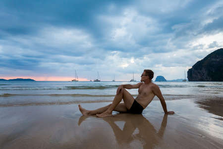 Tropical sunset landscape on Koh Mook island in Thailand. Handsome man relaxing on beach taken on Charlie beach, Haad Sai Yao - Haad Farang.の写真素材