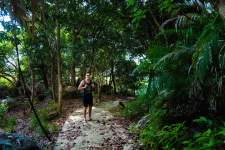 Young tourist having jungle trekking on tropical Tioman island in Malaysia. Beautiful nature of...