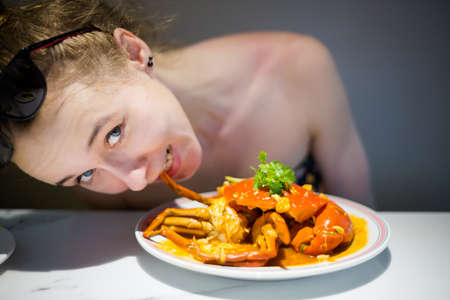 Young tourist eating Singapore style hot chilli crab served on China Town. South east Asia seafood dish.の写真素材