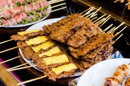 Fresh asian spicy cheese and pork skewers barbeque on local market. Traditional thai cuisine made of fresh ingredients.の写真素材