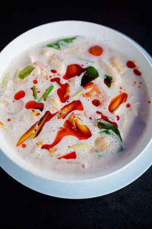 Fresh prepared asian aromatic Tom Kha Gai chicken soup in local restaurant in Bangkok. Traditional thai cuisine made of fresh ingredients.の写真素材