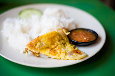 Fresh prepared malaysian egg omelette on rice with cucumber and sambal in local restaurant in Malacca. Traditional asian cuisine made of fresh ingredients.の写真素材