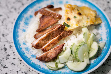 Delicious lunch in Vietnam: grilled meat with egg omelet and fresh cucumber on white rice. Traditional vietnamese cuisine served in local restaurant in Duong Dong, Phu Quoc, Vietnam.の写真素材