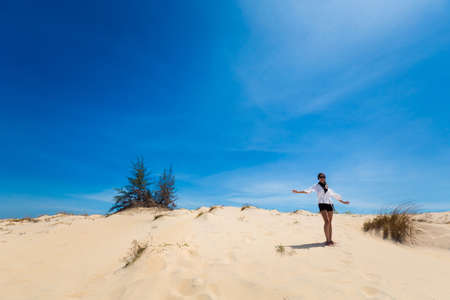 Beautiful caucasian girl having fun on White sand dunes in La Gi, Phan Tiet area in Vietnam. Landscape with blue sky on the south of Mui Ne.の写真素材