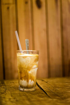 Glass of traditional vietnamese coconut ice coffee with a spoon and straw. Picture of popular cafe...