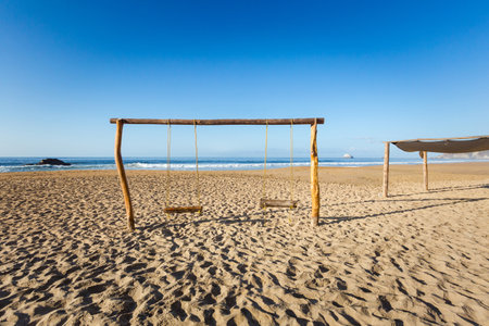 Beautiful Zipolite beach in Mexico. Swing on the blue skyの写真素材