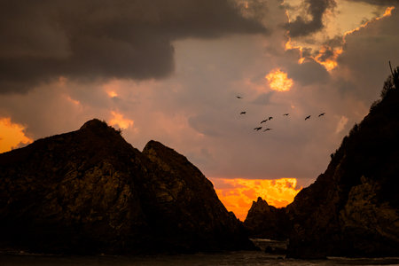Beautiful sunset behind rocks on Zipolite beach in Mexico. Landscape with golden sunの写真素材
