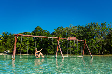 Beautiful female tourist relaxing on a swing in Laguna Bacalar in Mexico during kayak trip.の写真素材