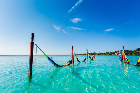 Beautiful white female tourist relaxing in a hammock in Laguna Bacalar in Mexico during kayak trip.の写真素材