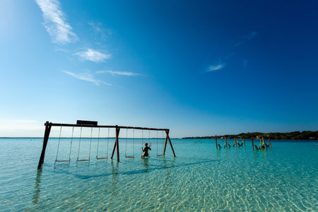 Beautiful female tourist relaxing on a swing in Laguna Bacalar in Mexico during kayak trip.の写真素材