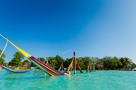 Beautiful white female tourist relaxing in a hammock in Laguna Bacalar in Mexico during kayak trip.の写真素材