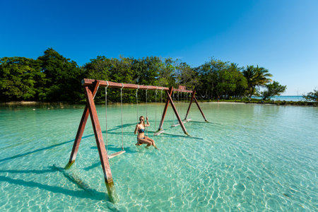Beautiful female tourist relaxing on a swing in Laguna Bacalar in Mexico during kayak trip.の写真素材