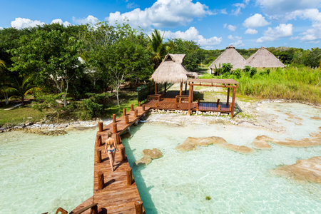 Beautiful landscape with young woman relaxing on a wooden pier in Laguna Bacalar in Mexico during kayak trip.の写真素材