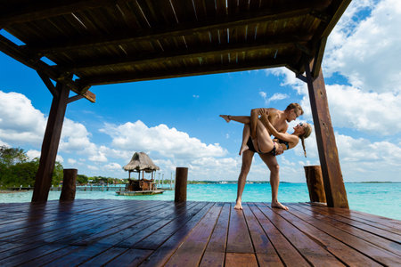 Beautiful landscape with happy young adult tourists couple relaxing on a wooden pier in Laguna Bacalar in Mexico during kayak trip.の写真素材