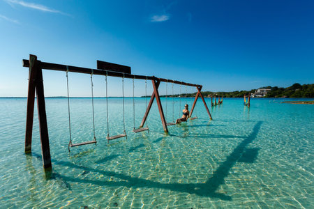 Beautiful female tourist relaxing on a swing in Laguna Bacalar in Mexico during kayak trip.の写真素材