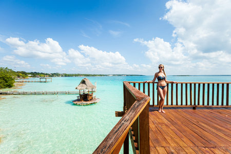 Beautiful landscape with young woman relaxing on a wooden pier in Laguna Bacalar in Mexico during kayak trip.の写真素材