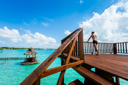 Beautiful landscape with young adult tourist relaxing on a wooden pier in Laguna Bacalar in Mexico during kayak trip.の写真素材