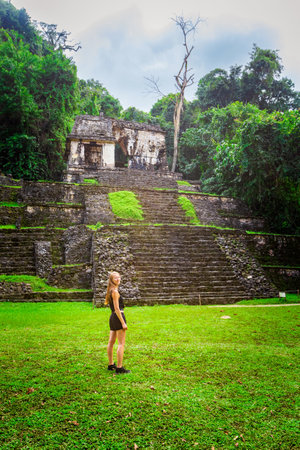 Beautiful young woman wearing black clothes in pyramids of Palenque archaeological site in Mexico. Vivid landscape photo.の写真素材