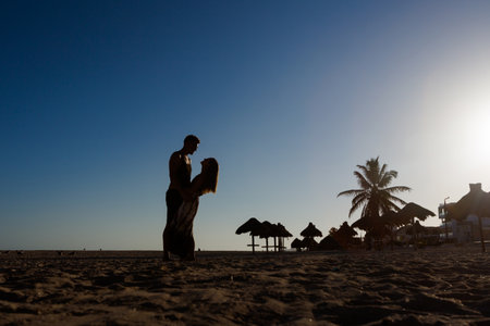Beautiful young happy tourists couple in Progreso beach, Mexico during sunny day. Romantic shot with White beach and blue sky.の写真素材