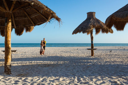 Beautiful young happy couple in Progreso beach, Mexico during a sunny day. White beach and blue sky.の写真素材