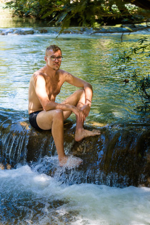 Young handsome man in Roberto Barrios cascadas park, Palenque in Mexico. Vivid landscape photo with lush green and crystal water during sunny day.の写真素材