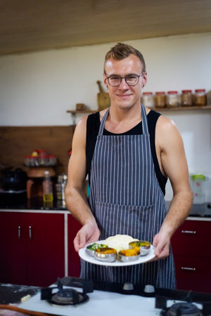 Young handsome caucasian man serving indian food. Picture of traditional India cuisine made of fresh ingredients taken during cooking class in Goaの写真素材