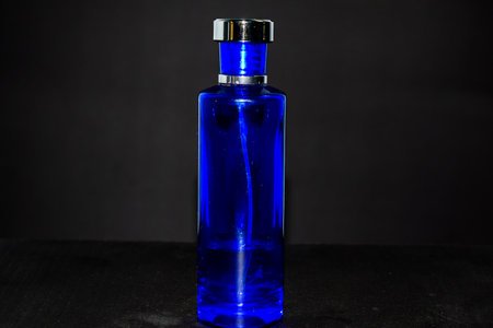 Transparent Dark Blue Bottle Perfume isolated black background for mock up designの写真素材