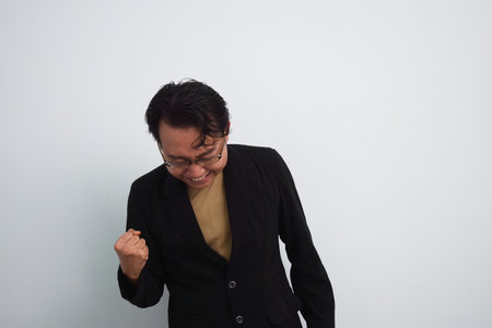 Happy asian businessman shout loud yeah with hands rise up isolated white backgroundの写真素材