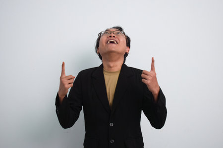 Joyful asian businessman with suit and casual shirt showing product or pointing gesture in isolated white backgroundの写真素材