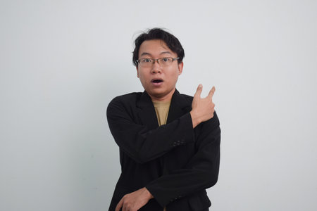 Asian businessman with suit and casual shirt showing pointing gesture in isolated white backgroundの写真素材