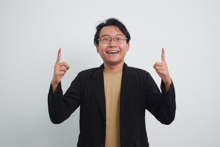 Joyful asian businessman with suit and casual shirt showing product or pointing gesture in isolated white backgroundの写真素材