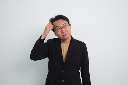 Thoughtful asian businessman with currious face think about solution in isolated white backgroundの写真素材