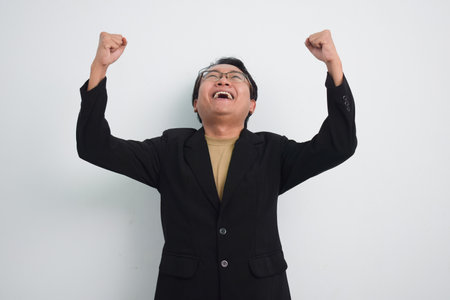 Happy asian businessman shout loud yeah with hands rise up isolated white backgroundの写真素材