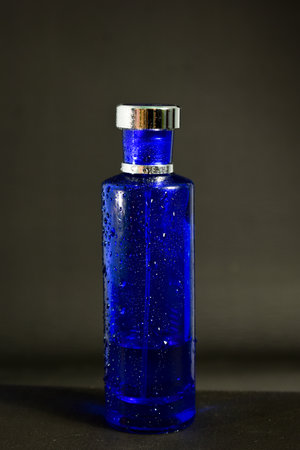Transparent Dark Blue Bottle Perfume isolated black background for mock up designの写真素材