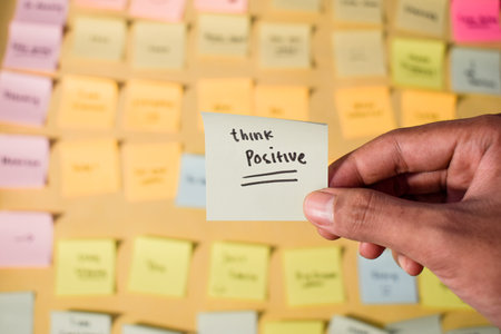 Hand hold sticky notes with words Think Positive. Motivational words for personal development, inspirational handwriting. Sticky notes backgroundの写真素材