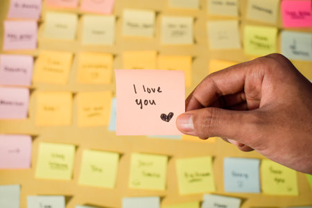 Hand hold sticky notes with words I love you. Motivational words for personal development, inspirational handwriting. Sticky notes backgroundの写真素材