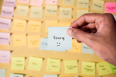 Hand hold sticky notes with words sorry, Motivational word for personal development, inspirational handwriting. Sticky note backgroundの写真素材