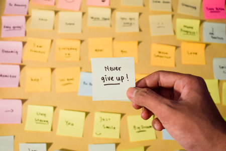 Hand hold sticky notes with words Never Give Up. Motivational words for personal development, inspirational handwriting. Sticky notes backgroundの写真素材