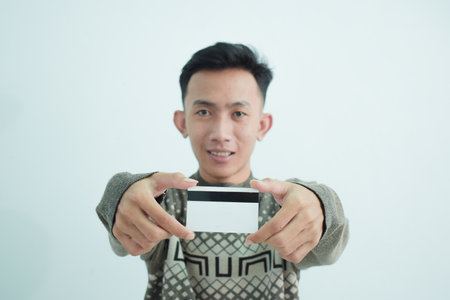 Joyful asian young men wear sweater and holding blank white card over white backgroundの写真素材