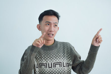 Asian young man showing pointing gesture with gesture and expression. Isolated on white backgroundの写真素材