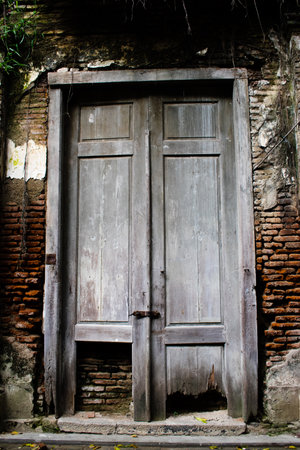 Big old broken wooden door on brick wall of historical building located in Kota Lama, Semarang City,...
