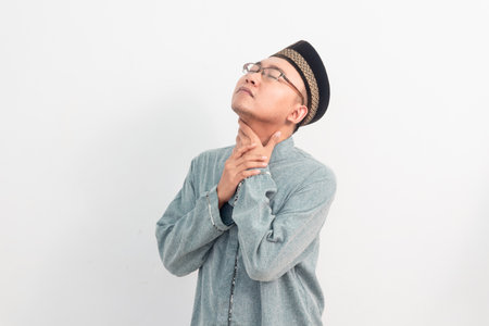 Asian Muslim man touching neck, thirsty gesture during fasting in Ramadan Eid Al Fitr and eid adha days celebration isolated white background. Islamic celebration concept.の写真素材