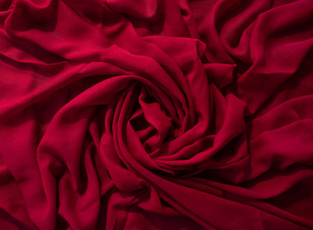Red fabric wavy spiral crumpled background texture.の写真素材