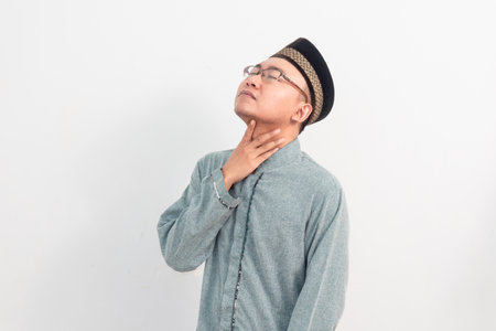 Asian Muslim man touching neck, thirsty gesture during fasting in Ramadan and eid days celebration...